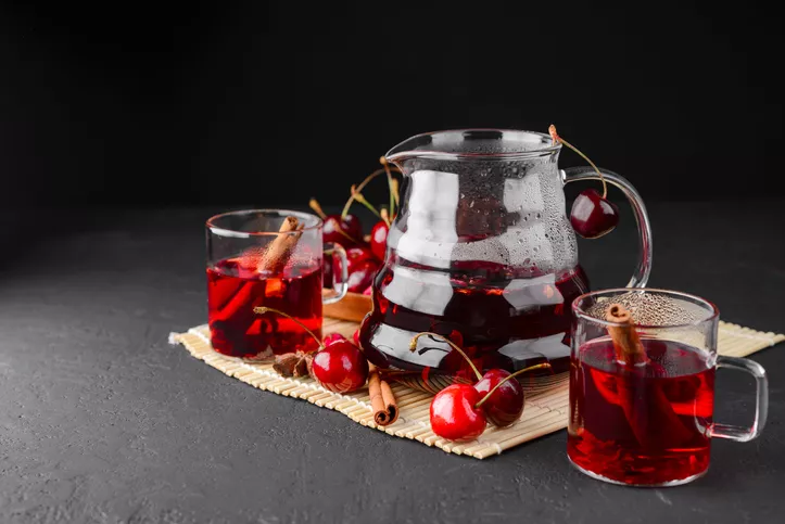 Freshly brewed tea with cherries on a dark concrete background